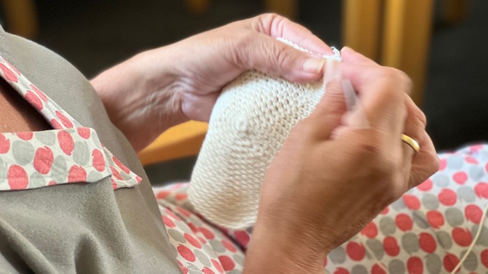 En person sitter og stråler en hvid trøje.