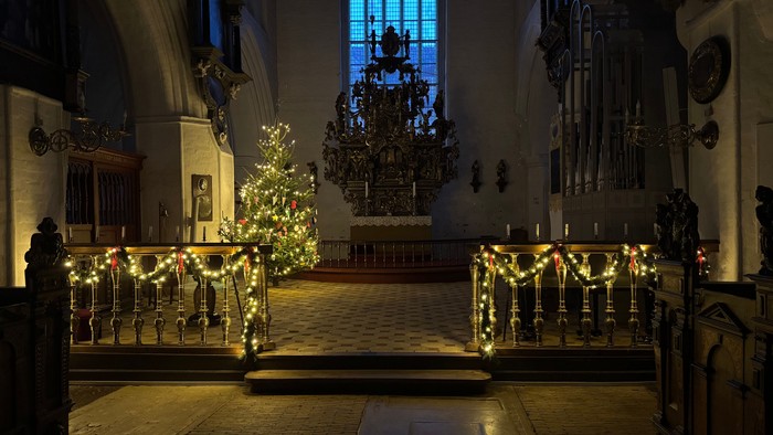 Indre del af kirke med juletree og lys.