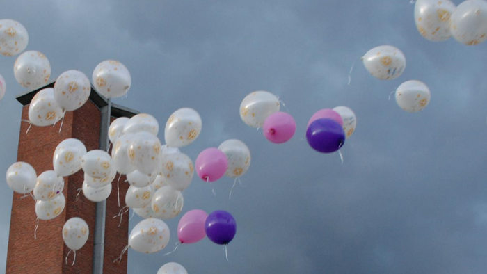 En del balloner flyver op i himlen, blå og rosa blandet med hvide