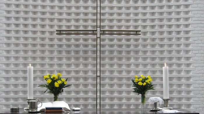 Moderne kirkealter med kors, stearinlys og blomster