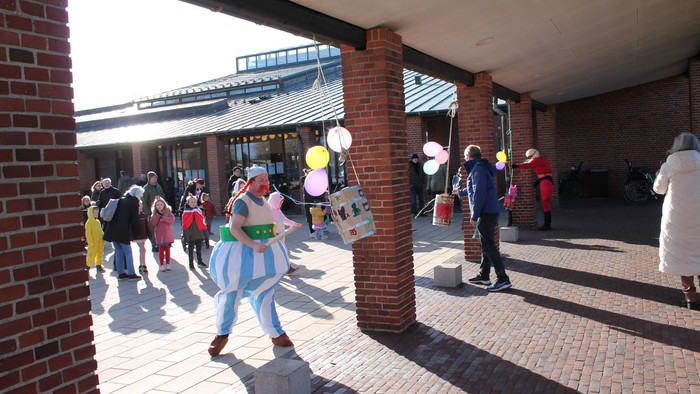 Børn i kostumer går udenfor en murstensbygning.