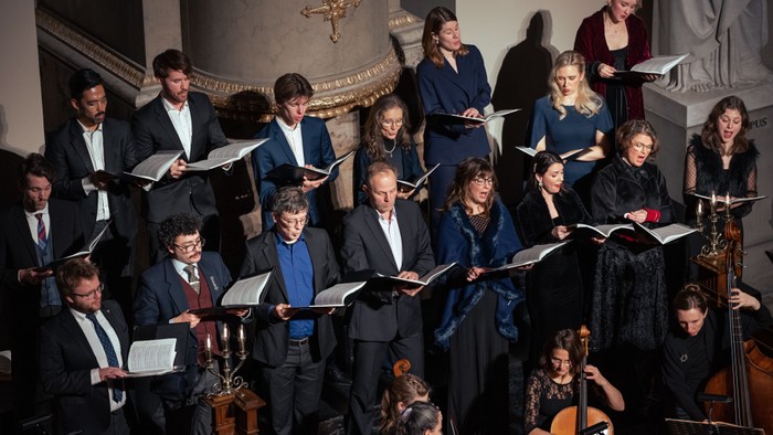 En kirkekor med mænd og kvinder, der synger og spiller instrumenter.