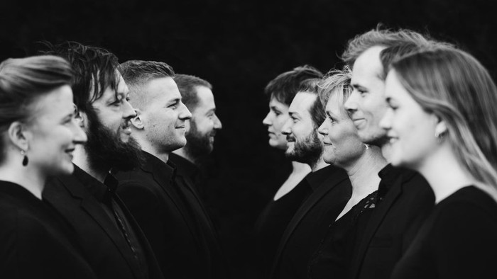 Gruppe af mennesker i sort tøj, stående på række.