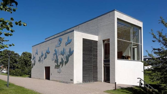 Moderne bygning med blå fugle-muraler og store vinduer