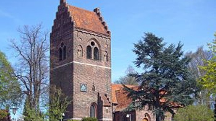 En gammel kirke med tårn og murer i en by.