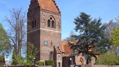 En rød murstenskirke med tårn og klokke.