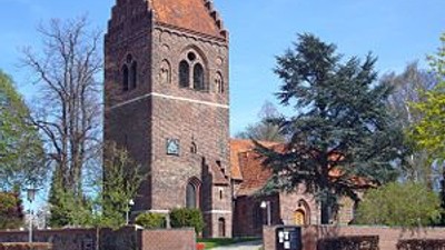 En gammel kirke med tårn og murer i en by.