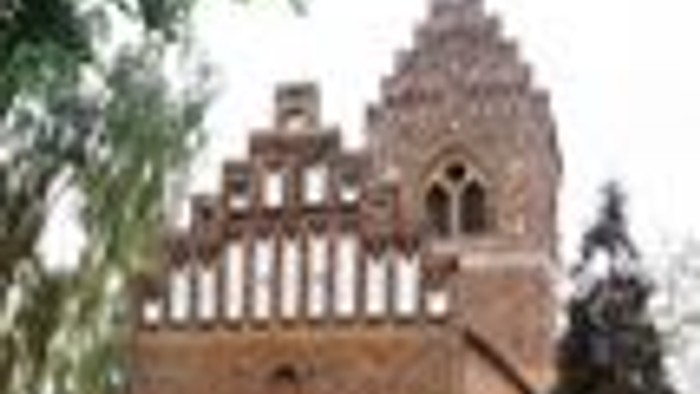 En stor murstensbygning med buede vinduer og et urtårn.