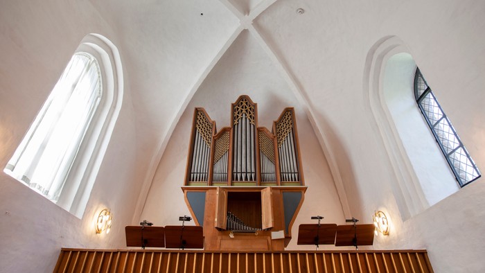 En kirke med orgel og bænke under to store buefönster