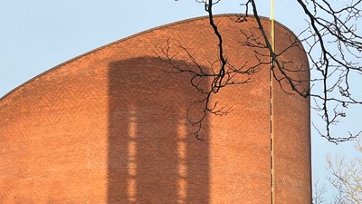 Det er et stort rødt murstensbygning med en lang skygge.