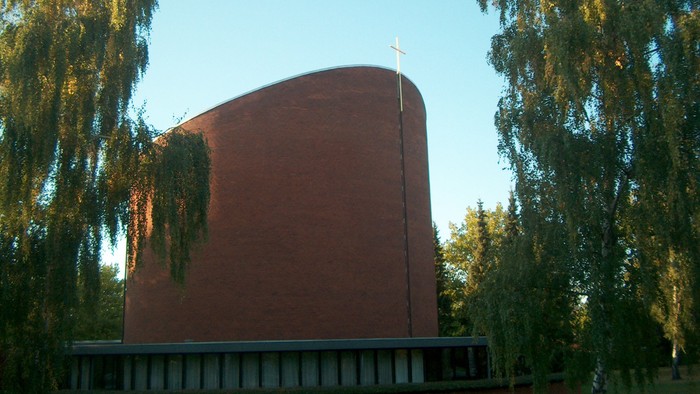 Rødt kirkebygning med tårn mellem træer