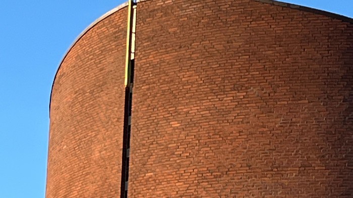 En stor mørk murstenskirke med et guldæret kors på toppen.