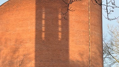 Det er et stort rødt murstensbygning med en lang skygge.