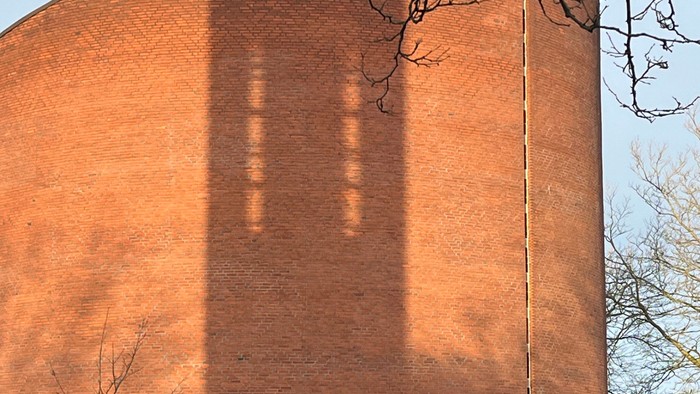 Det er et stort rødt murstensbygning med en lang skygge.