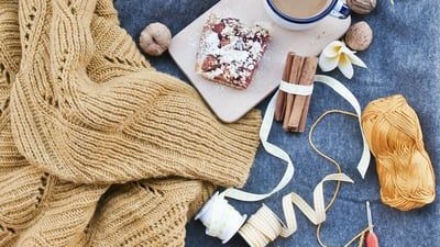 Gemütliche Szene mit Strickutensilien, Tee und Gebäck auf blauem Stoff