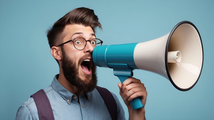 Mann mit Brille und Bart schreit in ein Megafon.