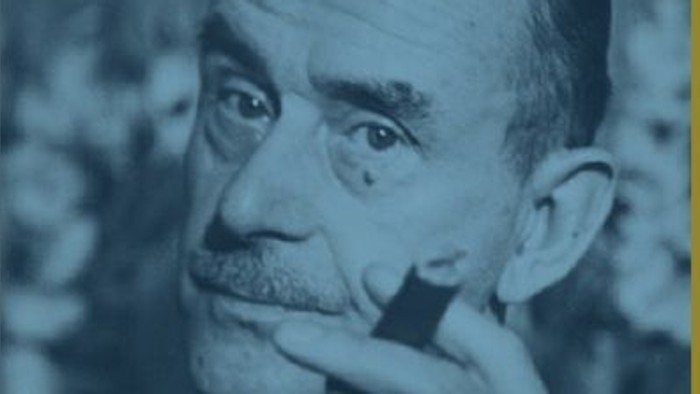 Ein älterer Mann mit Schnurrbart, der nachdenklich in die Kamera schaut.
