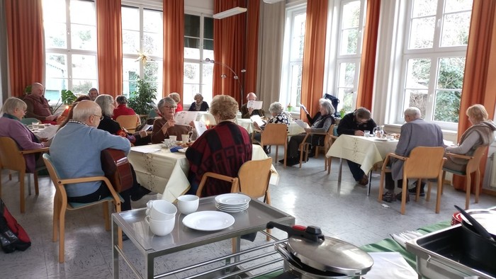 Senioren essen in einem hellen Speisesaal mit großen Fenstern.