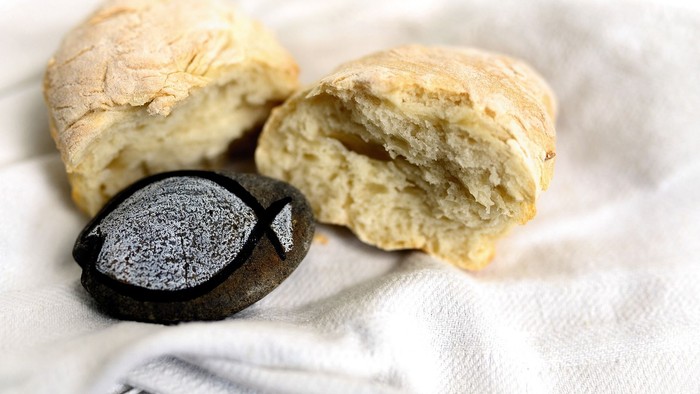 Zwei Stücke Brot und eine kleine Schale auf einem Tuch