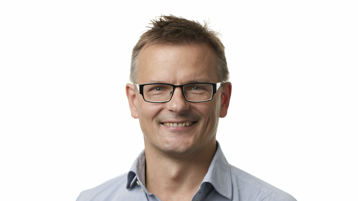 Mand med briller og blå skjorte.