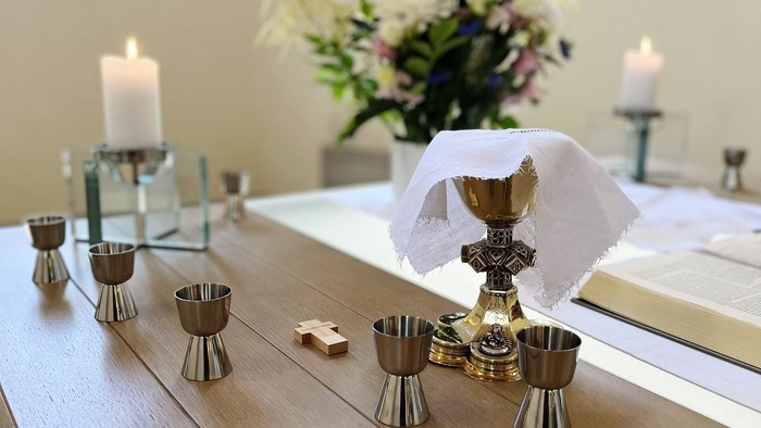 Tisch mit Kerzen, Kelch und Blumen