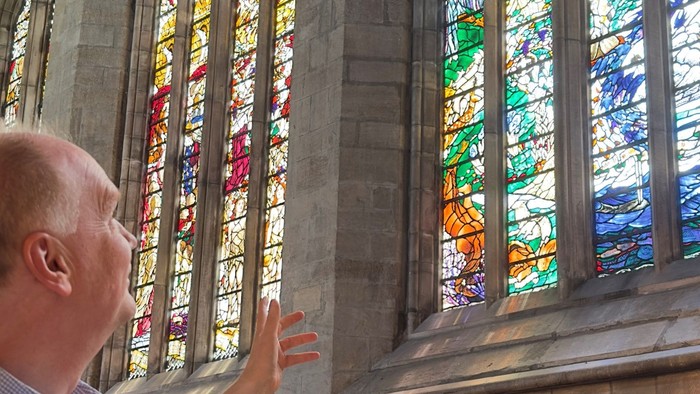 Man admiring colorful stained glass windows in a church.