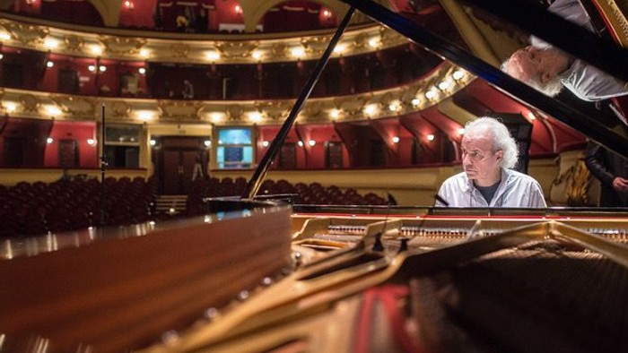 Mann spielt Klavier in einem großen Konzertsaal.