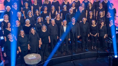 Große Gruppe von Sängerinnen und Sängern auf Bühne bei Konzert