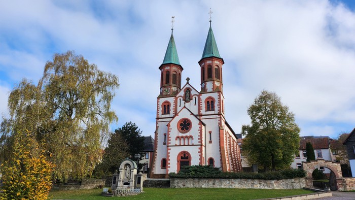 Weißer Kirchturm mit grüner Spitze vor blauem Himmel