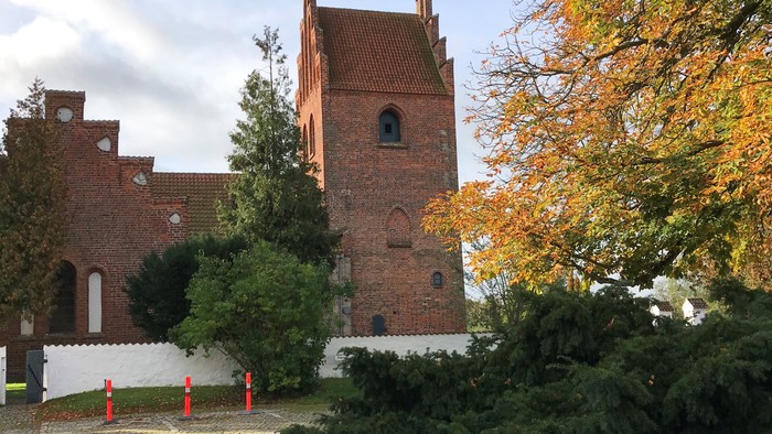 Et rødt teglmurstenshus med tårn og træer i forgrunden