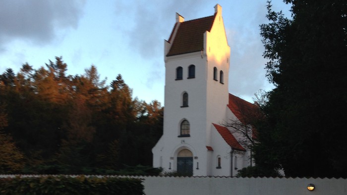 En lille kirke med tårn og rødt tag i skumbrødre.
