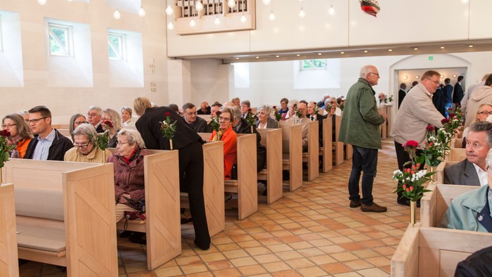 En kirke med folk, der sidder på bænke og taler med hinanden.