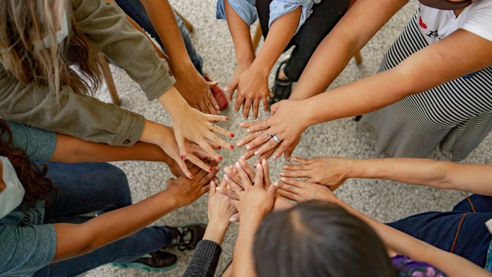 Eine Gruppe von Menschen bildet einen Kreis und hält sich an den Händen.