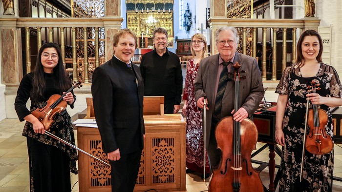Et strygekvartet og en pianist poser sammen i en prægtig indendørs omgivelse med klassiske instrumenter.