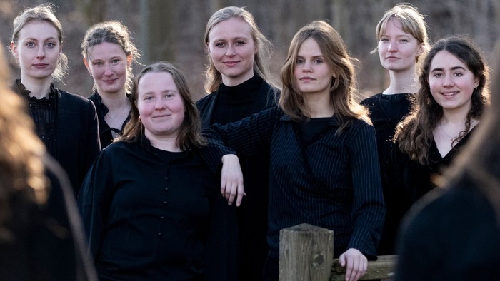 En gruppe unge piger står sammen i skoven, alle klædt i sort.