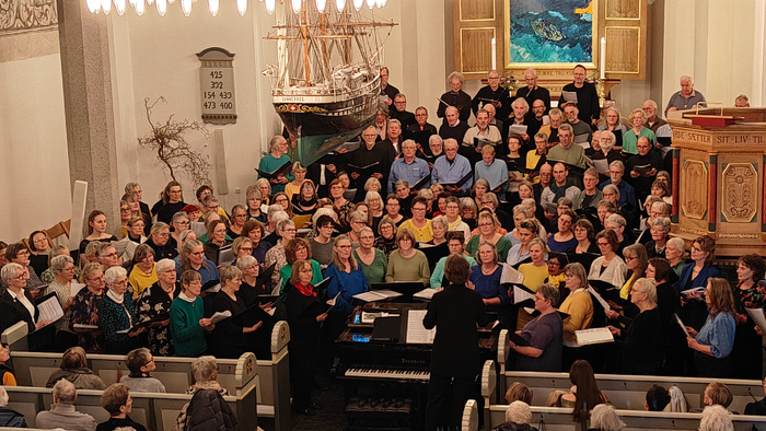 En stor kirkefuld med en kor og publikum under en prædiken.