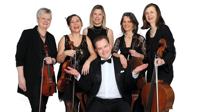 Eine Gruppe von fünf Musikern mit Streichinstrumenten posiert fröhlich