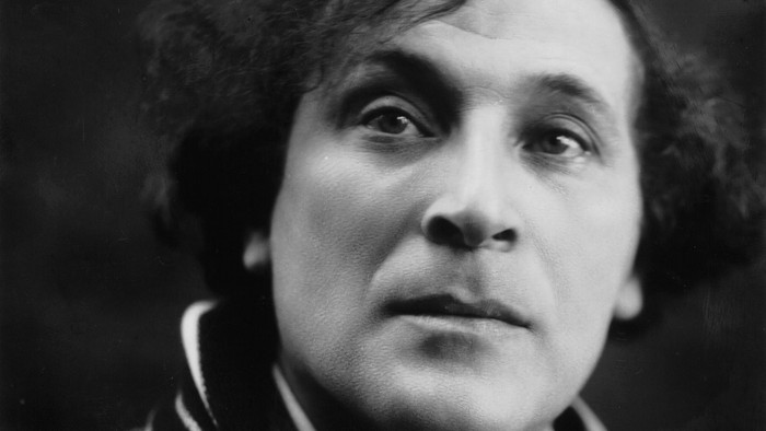 Eine Frau mit Krawatte und Schal posiert für ein Schwarz-Weiß-Foto.