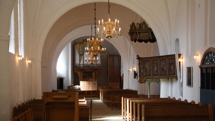 Indenrigsrom i kirke med orgel og bænke.