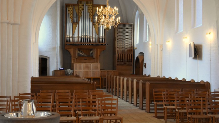 Indenrigspart af kirke med orgel og træbænke.