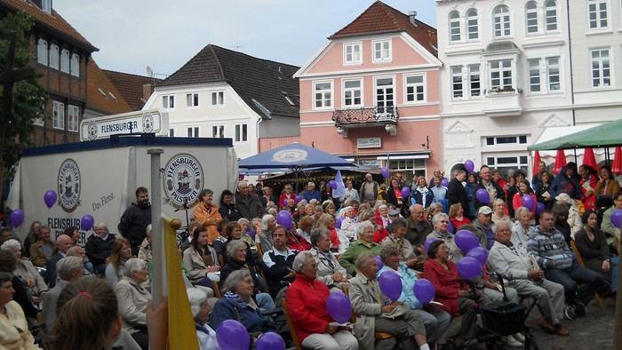 Große Menschenmenge auf einem Platz mit Luftballons und Bühne