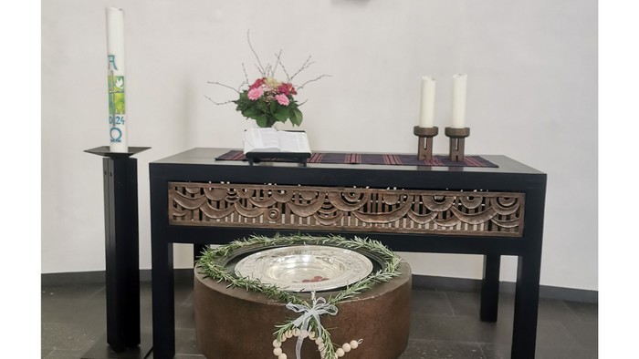 Ein Altar mit Kreuz, Kerzen und Blumen in einem Raum