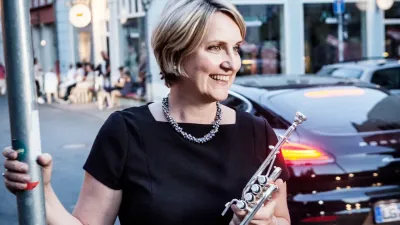 Frau spielt Flöte auf belebter Straße