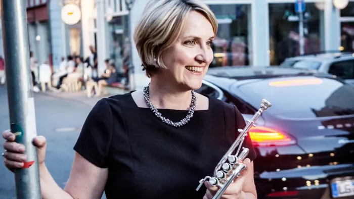 Frau spielt Flöte auf belebter Straße