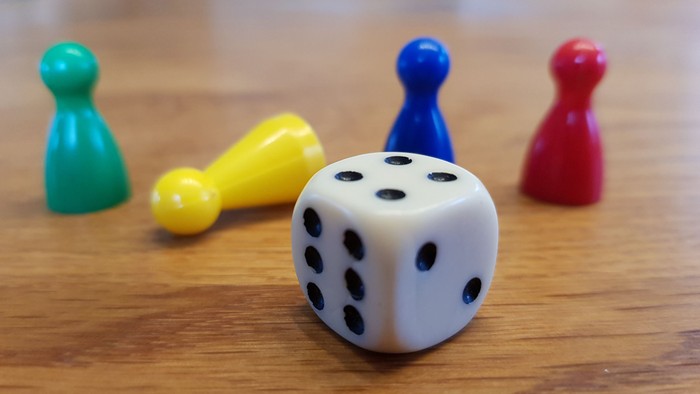 Ein Würfel mit 4 bunten Brettspielfiguren