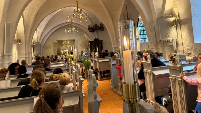 En stor kirkeindendomsrum med høje buer og mange lysstaker.