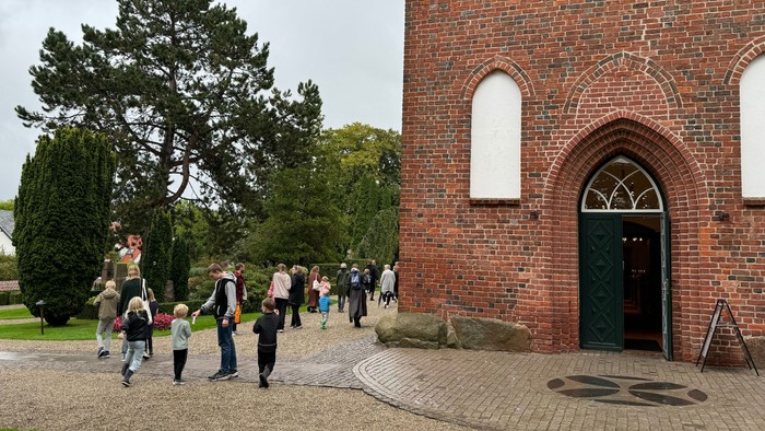 En gruppe af mennesker går ud af en rød murstenskirke.