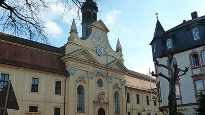 Historische Kirche mit verzierter Fassade und Uhrturm vor klarem blauem Himmel.