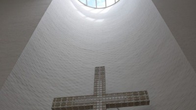 En stor, metallisk korsformet struktur i et rum med et rund vindue i taket.