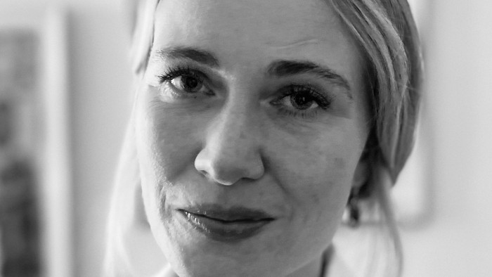 Et sort-hvidt portræt af en kvinde iført en hvid bluse, der kigger direkte på kameraet.